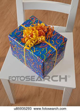 Stock Image - USA, Illinois, Metamora, Colorful present on chair. Fotosearch