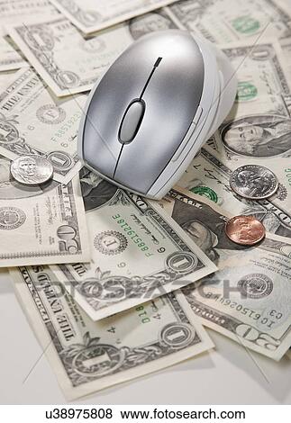 Stock Photo - USA, Illinois, Metamora, Computer mouse and US coins lying on paper money. Fotosearch