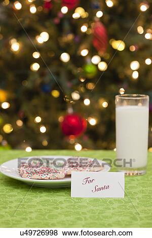 Stock Photo - USA, Illinois, Metamora, Cookies, milk and note to Santa Claus, Christmas tree in background. Fotosearch