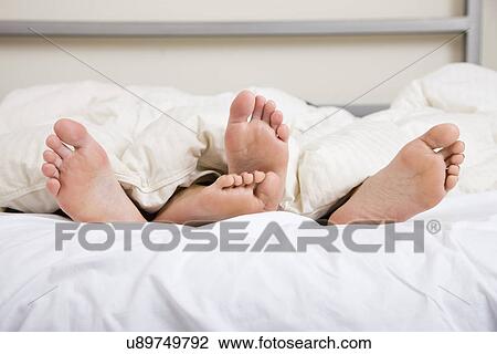 Stock Image - USA, Illinois, Metamora, Couple lying in bed. Fotosearch