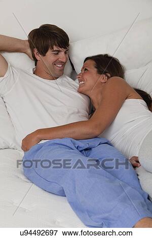 USA, Illinois, Metamora, couple lying down in bed and smiling face to face View Large Photo Image Stock Photo - USA, Illinois, Metamora, couple lying down in bed and smiling face to face. Fotosearch