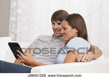 USA, Illinois, Metamora, couple sitting on sofa and reading Digital Tablet View Large Photo Image Stock Photo - USA, Illinois, Metamora, couple sitting on sofa and reading Digital Tablet. Fotosearch