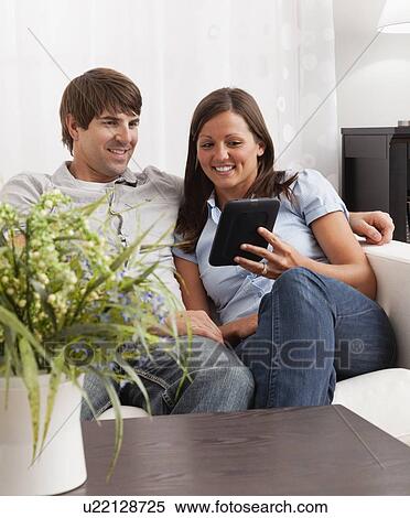 USA, Illinois, Metamora, couple sitting in living room and reading Digital Tablet View Large Photo Image Stock Photography - USA, Illinois, Metamora, couple sitting in living room and reading Digital Tablet. Fotosearch