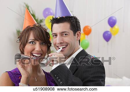 Stock Photo - USA, Illinois, Metamora, Couple with noisemakers at New Year's Eve party. Fotosearch