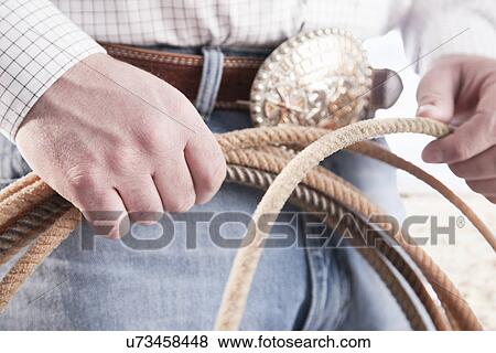 Stock Photo - USA, Illinois, Metamora, Cowboy holding lasso, mid section. Fotosearch