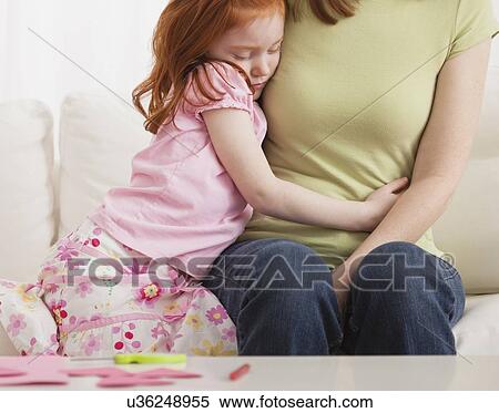 Stock Photography - USA, Illinois, Metamora, Daughter (4-5) and mother embracing on sofa. Fotosearch