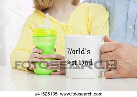 Stock Photography - USA, Illinois, Metamora, Daughter (6-7) and father holding mugs. Fotosearch
