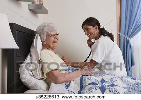 USA, Illinois, Metamora, Doctor examining senior woman sitting in bed View Large Photo Image Stock Image - USA, Illinois, Metamora, Doctor examining senior woman sitting in bed. Fotosearch