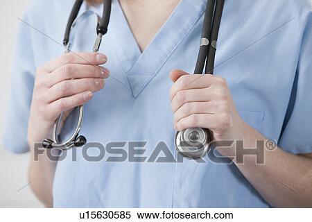 Stock Photography - USA, Illinois, Metamora, Doctor's hands holding stethoscope, mid section. Fotosearch