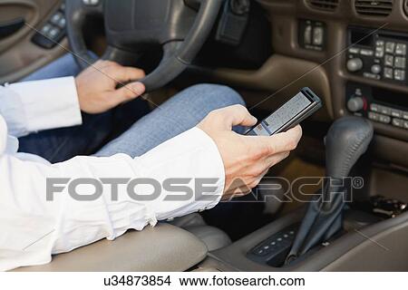 Picture - USA, Illinois, Metamora, driver's hands holding cell phone. Fotosearch