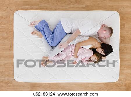Picture - USA, Illinois, Metamora, Family sleeping on mattress. Fotosearch