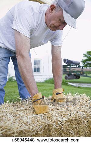USA, Illinois, Metamora, Farmer lifting hay bale on farm View Large Photo Image Stock Photo - USA, Illinois, Metamora, Farmer lifting hay bale on farm. Fotosearch