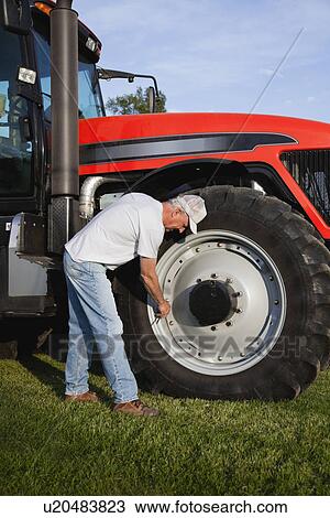 Stock Image - USA, Illinois, Metamora, Farmer repairing tractor wheel. Fotosearch
