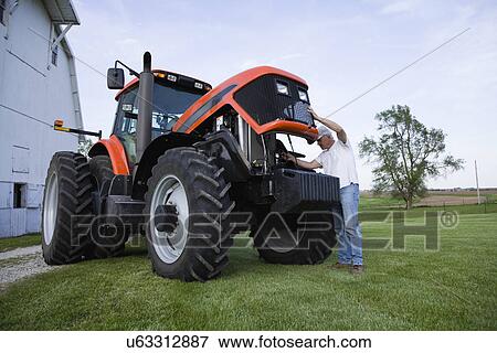 Stock Photo - USA, Illinois, Metamora, Farmer checking tractor engine. Fotosearch