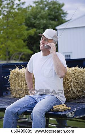 Stock Photography - USA, Illinois, Metamora, Farmer using mobile phone on truck. Fotosearch