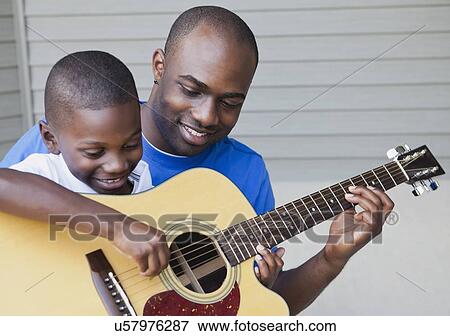 Stock Photo - USA, Illinois, Metamora, Fathers and son (6-7) playing guitar. Fotosearch