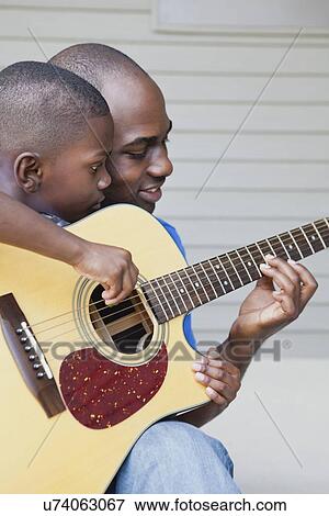 USA, Illinois, Metamora, Fathers and son (6-7) playing guitar View Large Photo Image Stock Photo - USA, Illinois, Metamora, Fathers and son (6-7) playing guitar. Fotosearch