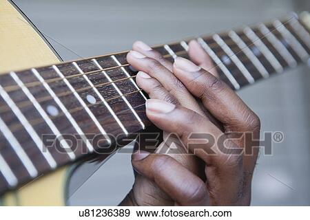 Stock Photo - USA, Illinois, Metamora, Fathers and son (6-7) hands on guitar's neck. Fotosearch