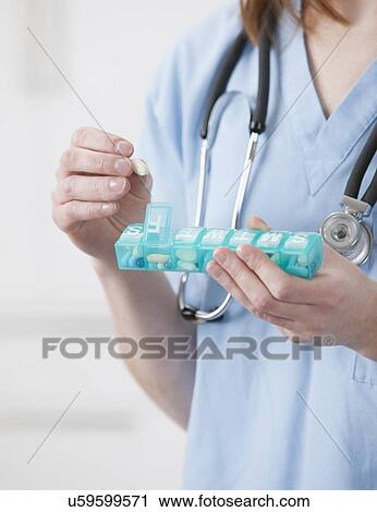 Stock Image - USA, Illinois, Metamora, Female doctor putting pill into pill container. Fotosearch