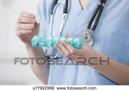 USA, Illinois, Metamora, Female doctor putting pill into pill container View Large Photo Image Stock Photo - USA, Illinois, Metamora, Female doctor putting pill into pill container. Fotosearch