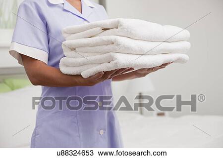 USA, Illinois, Metamora, Female hotel maid holding stack of folded towels, mid section View Large Photo Image Stock Image - USA, Illinois, Metamora, Female hotel maid holding stack of folded towels, mid section. Fotosearch