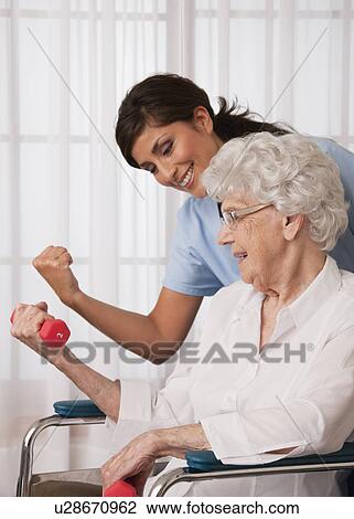 USA, Illinois, Metamora, Female nurse assisting senior woman using hand weights View Large Photo Image Stock Image - USA, Illinois, Metamora, Female nurse assisting senior woman using hand weights. Fotosearch