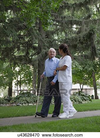 USA, Illinois, Metamora, Female nurse and senior man walking in park View Large Photo Image Stock Image - USA, Illinois, Metamora, Female nurse and senior man walking in park. Fotosearch