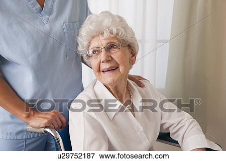 USA, Illinois, Metamora, Female nurse assisting senior woman on wheelchair View Large Photo Image Stock Photo - USA, Illinois, Metamora, Female nurse assisting senior woman on wheelchair. Fotosearch