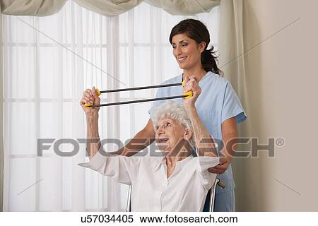 USA, Illinois, Metamora, Female nurse assisting senior woman on wheelchair using exercise band View Large Photo Image Stock Photography - USA, Illinois, Metamora, Female nurse assisting senior woman on wheelchair using exercise band. Fotosearch