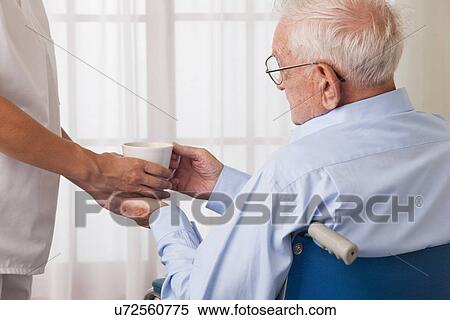 USA, Illinois, Metamora, Female nurse handing drink to senior man on wheelchair View Large Photo Image Stock Photography - USA, Illinois, Metamora, Female nurse handing drink to senior man on wheelchair. Fotosearch