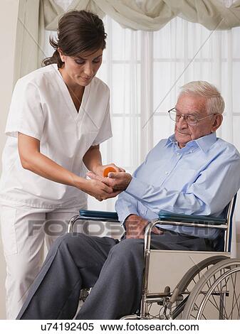 USA, Illinois, Metamora, Female nurse giving pills to senior man on wheelchair View Large Photo Image Stock Photography - USA, Illinois, Metamora, Female nurse giving pills to senior man on wheelchair. Fotosearch
