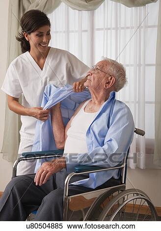 USA, Illinois, Metamora, Female nurse assisting senior man in dressing himself View Large Photo Image Stock Photography - USA, Illinois, Metamora, Female nurse assisting senior man in dressing himself. Fotosearch