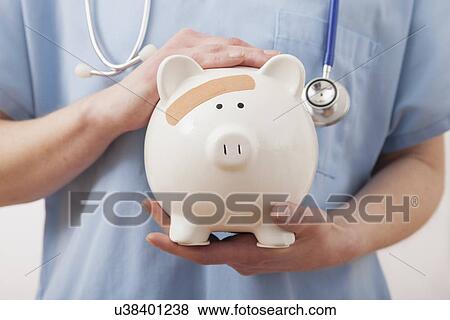 Stock Photo - USA, Illinois, Metamora, Female nurse's hands holding piggy bank. Fotosearch