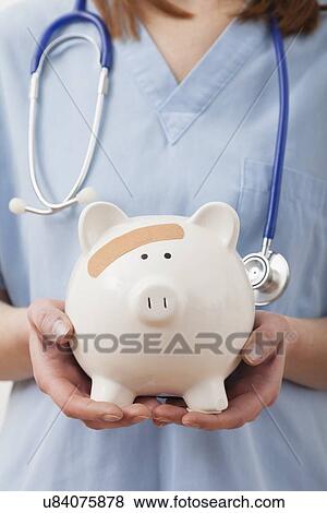 USA, Illinois, Metamora, Female nurse's hands holding piggy bank View Large Photo Image Stock Photo - USA, Illinois, Metamora, Female nurse's hands holding piggy bank. Fotosearch