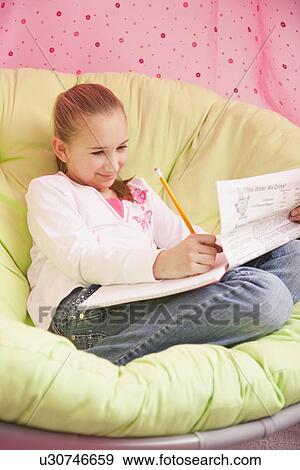 Stock Photo - USA, Illinois, Metamora, Girl (10-11) sitting on soft chair and writing. Fotosearch