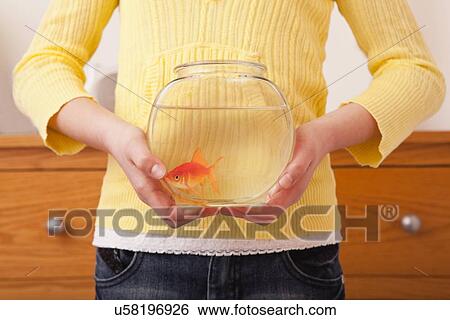 Stock Photograph - USA, Illinois, Metamora, Girl (10-11) holding golfish in fishbowl. Fotosearch