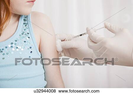 Stock Photo - USA, Illinois, Metamora, Girl (4-5) having vaccination in doctor' office. Fotosearch