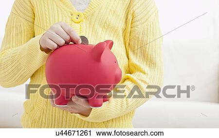 Stock Image - USA, Illinois, Metamora, Girl (6-7) holding red piggybank. Fotosearch