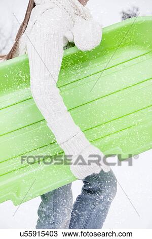 Stock Image - USA, Illinois, Metamora, girl (6-7) carrying sled. Fotosearch