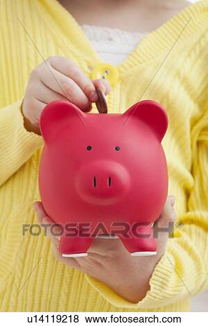 USA, Illinois, Metamora, Girl (6-7) putting coin into red piggybank View Large Photo Image Stock Photo - USA, Illinois, Metamora, Girl (6-7) putting coin into red piggybank. Fotosearch