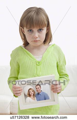 Stock Photo - USA, Illinois, Metamora, Girl (6-7) holding photograph of couple. Fotosearch