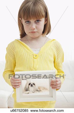 Stock Photography - USA, Illinois, Metamora, Girl (6-7) holding photograph of dog. Fotosearch