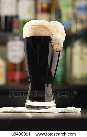 Stock Image - USA, Illinois, Metamora, Glass of dark beer on bar counter. Fotosearch