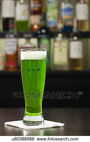 Stock Photo - USA, Illinois, Metamora, Glass of green beer on bar counter. Fotosearch