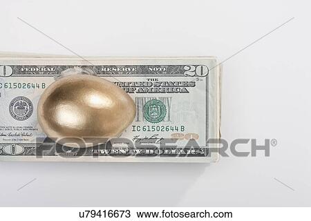 Stock Image - USA, Illinois, Metamora, Golden egg on top of US money. Fotosearch