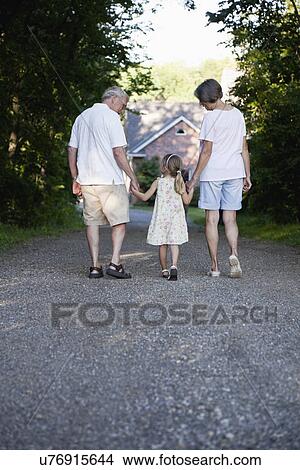 Picture - USA, Illinois, Metamora, grandparents walking with granddaughter (4-5). Fotosearch