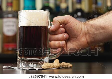 USA, Illinois, Metamora, Hand holding glass of dark beer in bar View Large Photo Image Stock Image - USA, Illinois, Metamora, Hand holding glass of dark beer in bar. Fotosearch