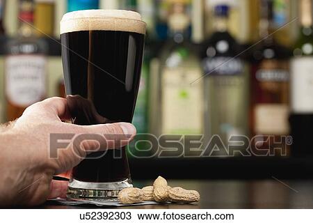 USA, Illinois, Metamora, Hand reaching for glass of dark beer in bar View Large Photo Image Stock Image - USA, Illinois, Metamora, Hand reaching for glass of dark beer in bar. Fotosearch