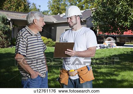 Stock Photograph - USA, Illinois, Metamora, Home owner with construction worker holding bill. Fotosearch