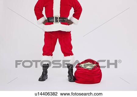 Stock Image - USA, Illinois, Metamora, low section of Santa Claus with sack of banknotes. Fotosearch